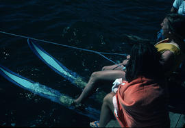 [Boy with water skis sitting on dock next to girl]