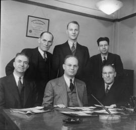 Harold Merilees and others gathered behind a desk