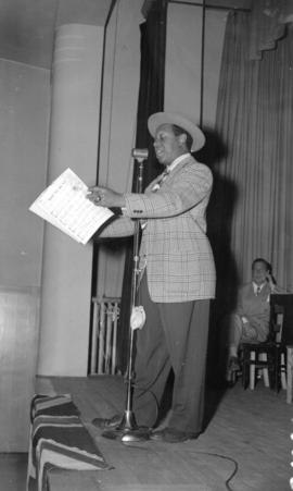 [Rochester (Eddie Anderson) at a microphone singing, during Jack Benny's visit to Vancouver]