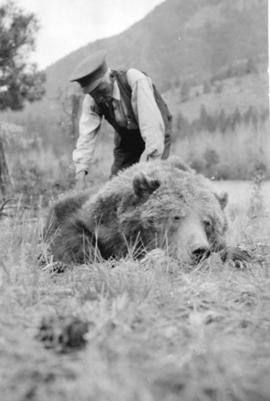 [Francis Gott tending to a dead grizzly bear]