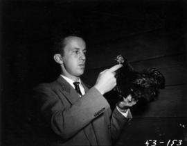 Man holding dark-colored chicken in poultry competition