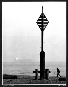 [Man walking along shore at] Spanish Banks