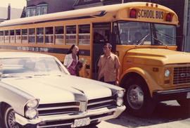 [Shirley Chan?] and unidentified male standing in front of school bus