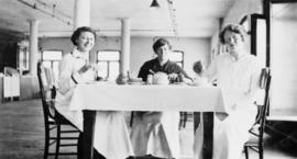 Three women seated at table with tea