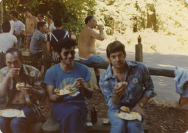 Portrait of three unidentified people eating outdoors