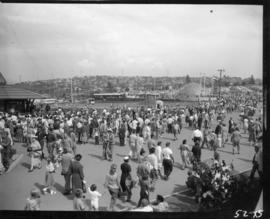 View of crowd and CKWX remote studio, Livestock bowl, and Armed Forces exhibit on P.N.E. grounds