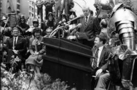 Speakers and guests around podium with press microphones