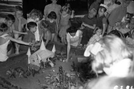 [Children gathered around a sandlot display during a competition]