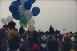 Man handing out balloons to children