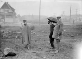 Two men in uniform, one man in a long coat