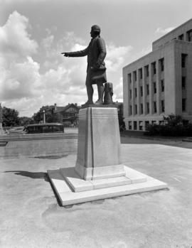 [Statue of George Vancouver in front of City Hall with Yukon Street in the background]