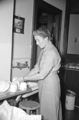 [Red Cross worker washing dishes at a blood donor clinic]