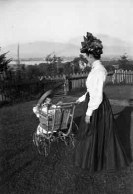 [Annie Louise Taylor with Theodore Pierce Taylor in chair with wheels in yard of home at Willow S...