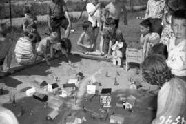 [Children gathered at a sandlot display during a competition]