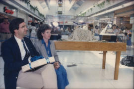 Unidentified man and woman seated beside display case