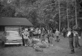 Group gathered outside of a log cabin