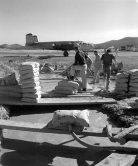 [Men mixing fire control chemicals with water in large pits for loading onto a water bomber]