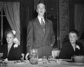 Man standing between two seated women