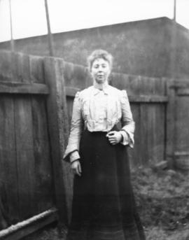 [Woman standing next to fence]