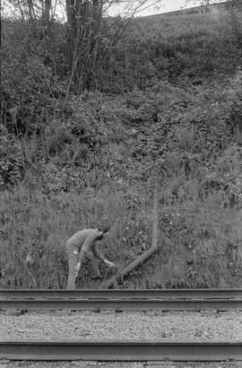 David Rodger inspecting pipe by railroad track