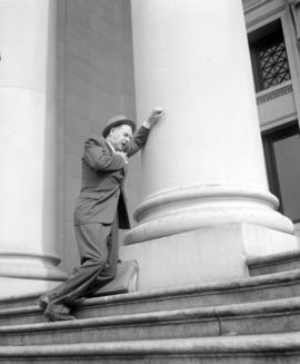 [Actor feigning a heart attack outside the courthouse taken as a still for a film production comp...