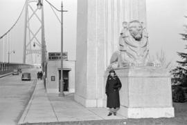 [A woman beside the lion sculpture at the entrance to the Lions Gate Bridge]