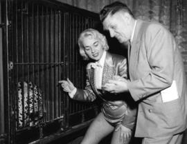 Man and circus performer posing with caged leopard