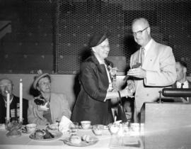 [Mr. W.C. Mainwaring presenting scissors to Mrs. H.B. Barton at luncheon to celebrate the start o...