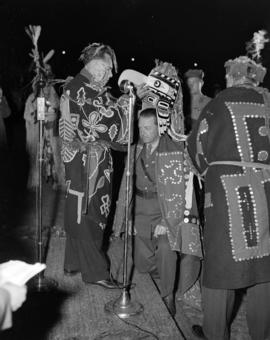 [Chief William Scow placing a mask over Lord Alexander's head during a ceremony confering an hono...