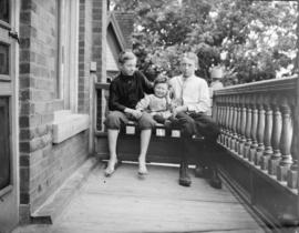 [Three children sitting on a front porch]