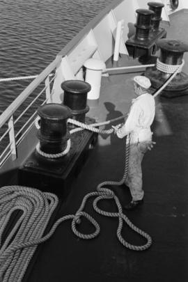 Casting off [man casting off the line to a large ship]