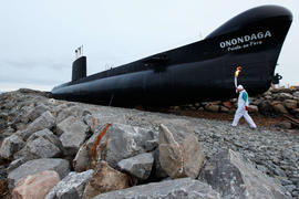 Day 32 Torchbearer 31 Andrew Mack carries the flame in front of the Onondaga ship in Rimouski, Qu...