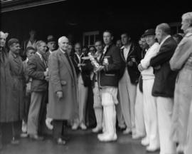 Cricket player holding a trophy in the shape of a totem pole, surrounded by a crowd