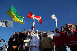 Day 75 Torchbearer 66 Cody Kahpeaysewat stands on the stage with the three First Nations chiefs i...