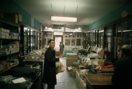Wing Hing Dry Goods owner Lin Bei-lian at counter in display area, and two other men