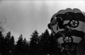 Man performing bike trick with hot air balloon in background