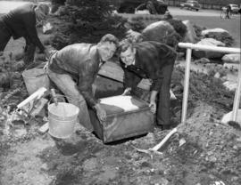 Putting time capsule into hole to be covered with Centuries Rock, Queen Elizabeth Park