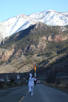 Day 100 Torchbearer runs down the street towards the mountains in British Columbia.