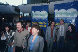 People singing into microphones at Vancouver's 99th birthday celebration