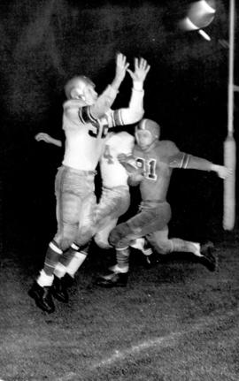 [A player catching a pass during the 43rd Grey Cup game at Empire Stadium]