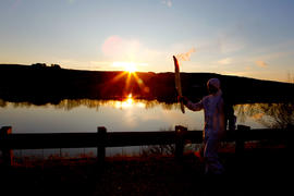Day 36 Torchbearer runs along the water at sunset in Quebec.