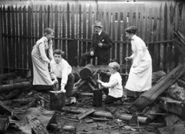 Unidentified family group sawing and splitting wood