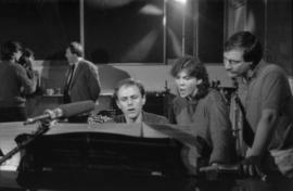 Group at piano in recording studio
