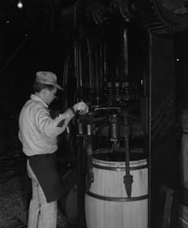 Worker at machine assembling staves into barrel