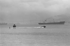 Small boat and freighter, Second Narrows Bridge in distance