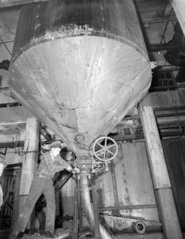 [A man operating a machine at] Pacific Mills