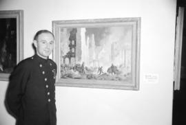 [Firefighter standing beside a painting at a firefighting art exhibit]