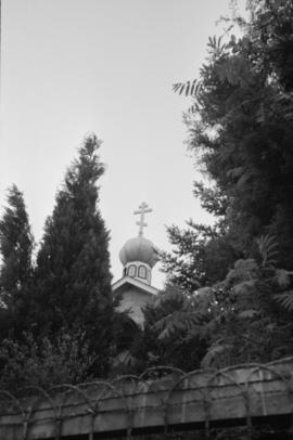 [810-813 East 13th Avenue - View of St. Nicolaus Russian Orthodox Church spire through trees]